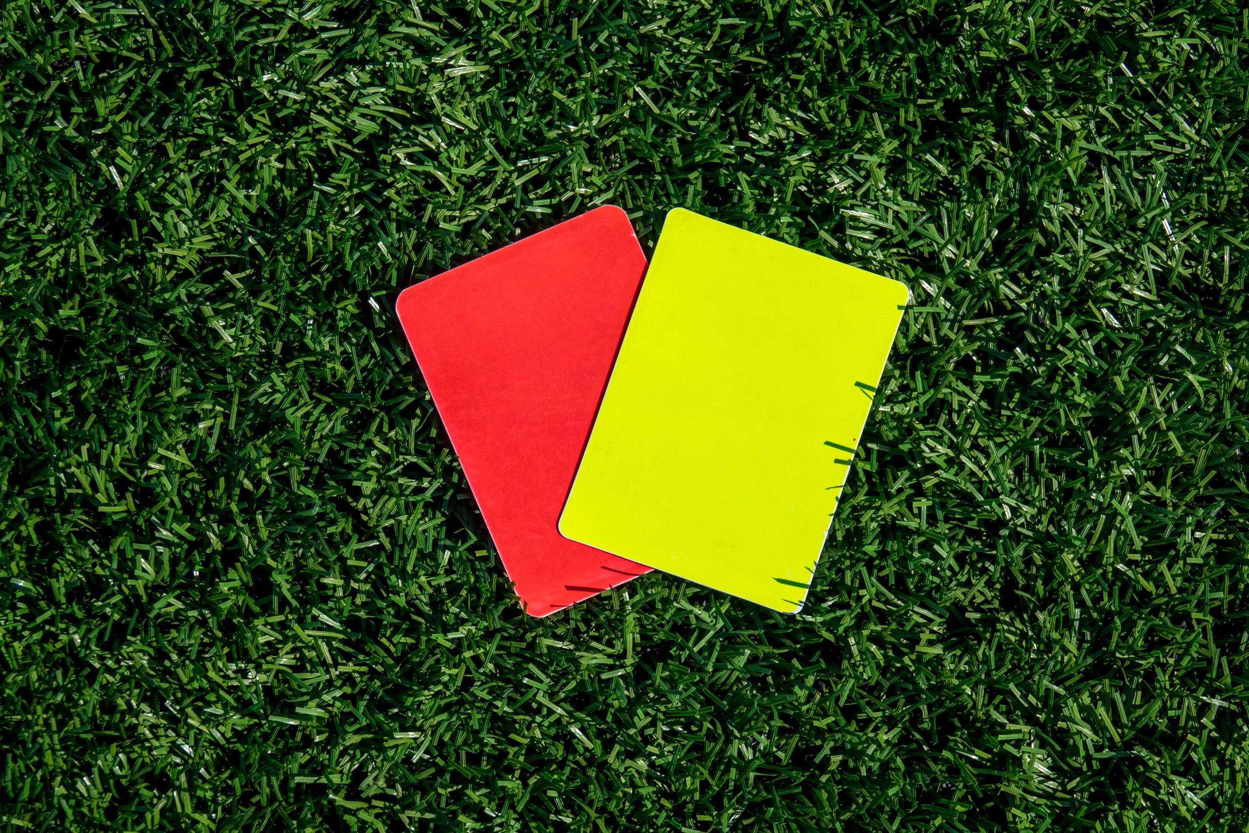 Referee soccer, football game, red and yellow cards on green grass. Two penalty cards for the referee